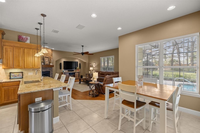 kitchen with pendant lighting, a stone fireplace, sink, light stone counters, and kitchen peninsula