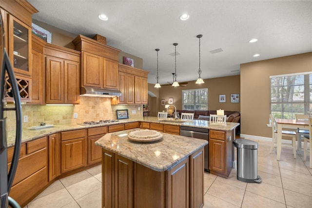 kitchen featuring kitchen peninsula, stainless steel appliances, sink, a kitchen island, and hanging light fixtures