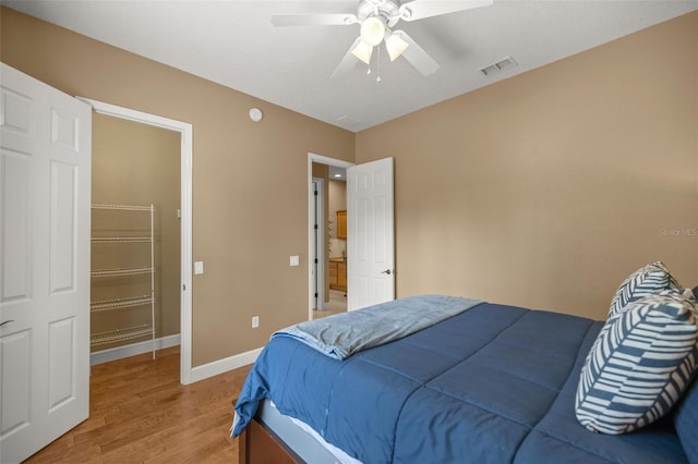 bedroom featuring a walk in closet, ceiling fan, a closet, and hardwood / wood-style floors