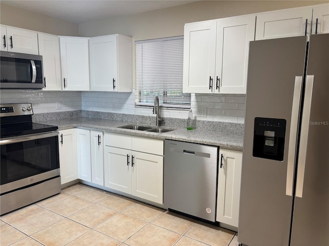 kitchen with stainless steel appliances, light tile patterned floors, decorative backsplash, white cabinetry, and sink