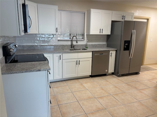 kitchen with sink, appliances with stainless steel finishes, light tile patterned flooring, and white cabinetry