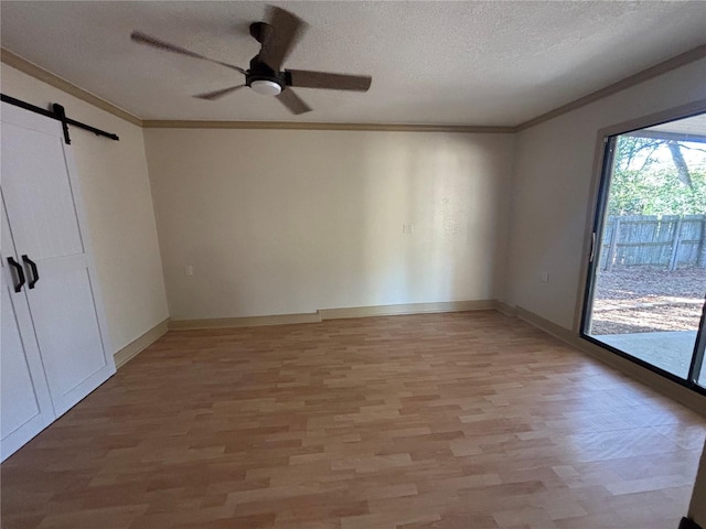 unfurnished room with crown molding, a barn door, and light hardwood / wood-style flooring