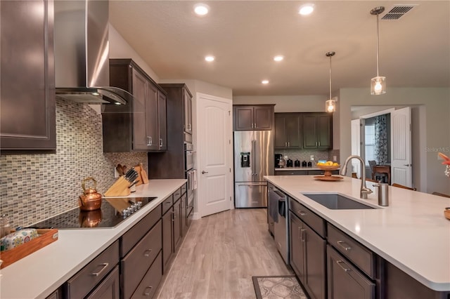 kitchen featuring decorative backsplash, sink, stainless steel appliances, and wall chimney range hood