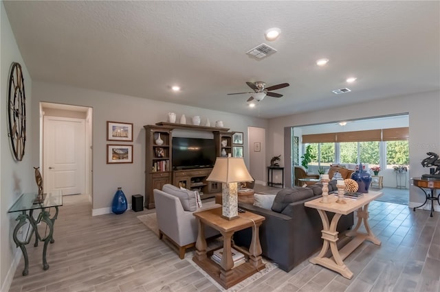 living room with a textured ceiling, light hardwood / wood-style flooring, and ceiling fan