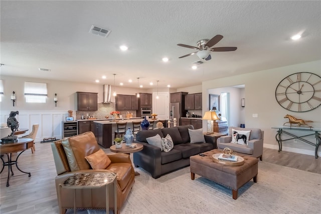 living room with light hardwood / wood-style flooring, beverage cooler, and ceiling fan