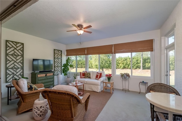 living room with carpet, ceiling fan, and a textured ceiling