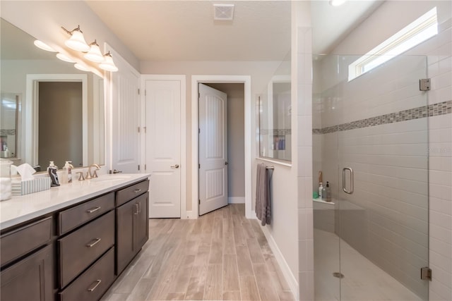 bathroom with wood-type flooring, vanity, and a shower with door