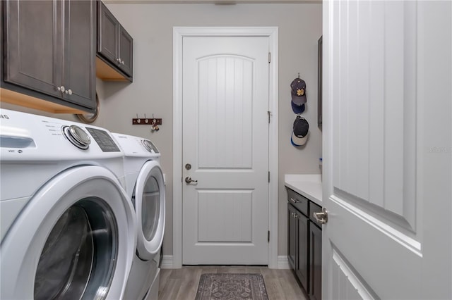 clothes washing area with cabinets, separate washer and dryer, and light hardwood / wood-style flooring