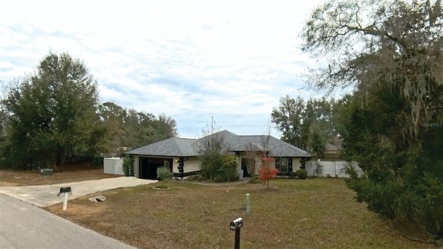 ranch-style house with a garage, concrete driveway, fence, and a front lawn