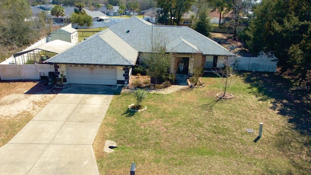 view of front of house with roof with shingles, fence, a garage, driveway, and a front lawn