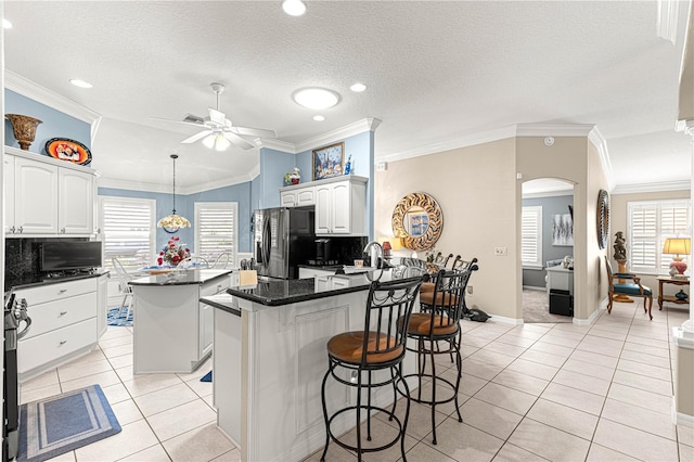 kitchen featuring a center island, stainless steel fridge with ice dispenser, decorative backsplash, white cabinets, and ornamental molding