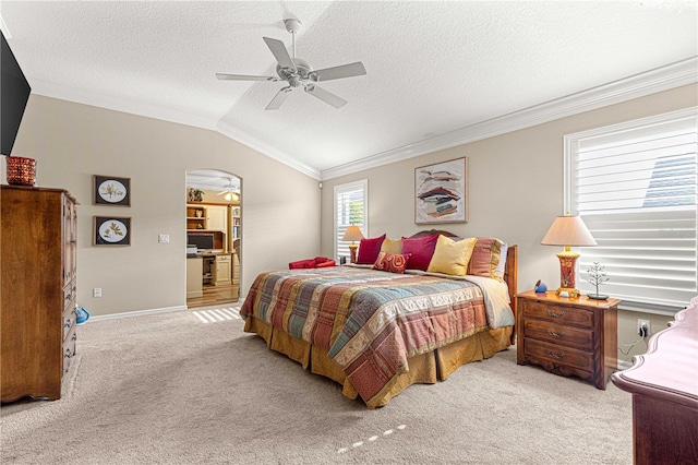 bedroom featuring lofted ceiling, light carpet, ensuite bathroom, ceiling fan, and ornamental molding