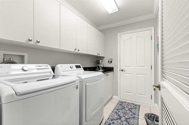 laundry area featuring cabinets, ornamental molding, a textured ceiling, washer and dryer, and light tile patterned floors