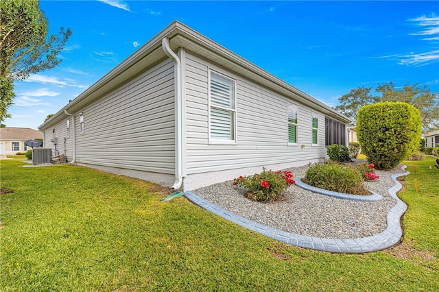 view of side of property with a lawn and central AC