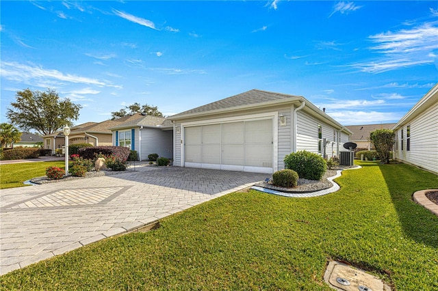 view of front of house featuring central AC unit, a front yard, and a garage