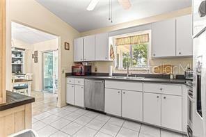 kitchen with ceiling fan, white cabinets, stainless steel dishwasher, and lofted ceiling