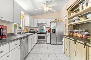 kitchen with white cabinets, sink, stainless steel appliances, and vaulted ceiling