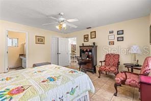 tiled bedroom with ensuite bath and ceiling fan