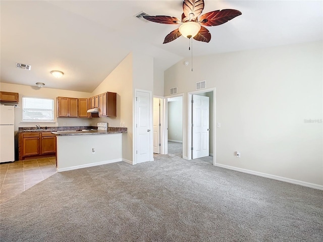 kitchen featuring ceiling fan, white refrigerator, stove, vaulted ceiling, and light carpet