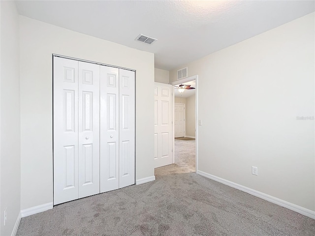 unfurnished bedroom with light colored carpet and a closet