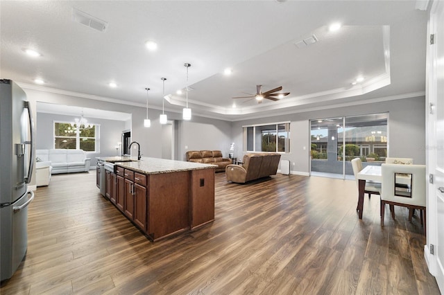 kitchen with a center island with sink, decorative light fixtures, stainless steel fridge, and a tray ceiling