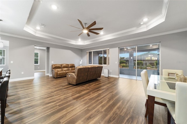 living room featuring a tray ceiling, dark hardwood / wood-style flooring, and ornamental molding