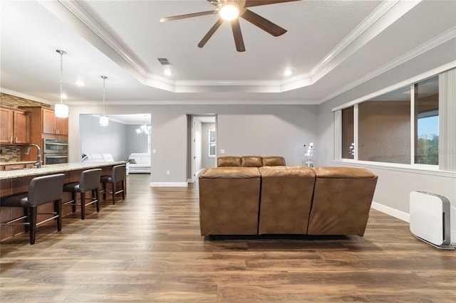 living room featuring ceiling fan, dark hardwood / wood-style flooring, crown molding, and a tray ceiling