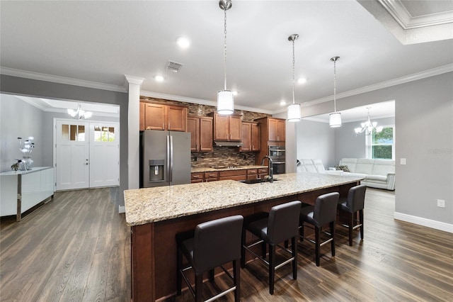 kitchen featuring appliances with stainless steel finishes, tasteful backsplash, sink, pendant lighting, and a notable chandelier