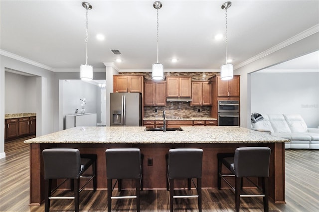 kitchen with a large island, sink, tasteful backsplash, a breakfast bar, and appliances with stainless steel finishes