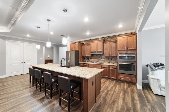 kitchen with sink, tasteful backsplash, decorative light fixtures, a center island with sink, and appliances with stainless steel finishes