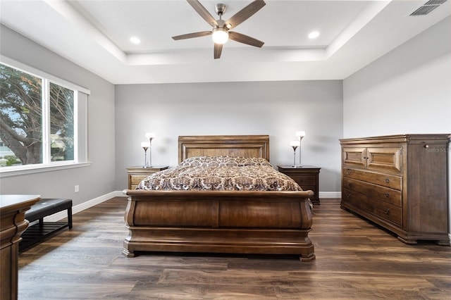 bedroom featuring a raised ceiling, ceiling fan, and dark wood-type flooring