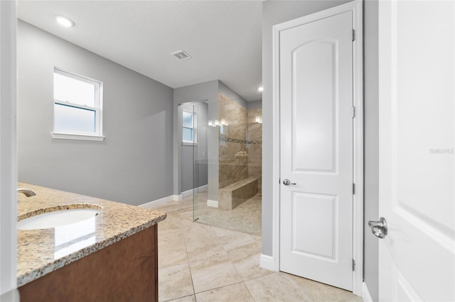 bathroom with tiled shower, vanity, and tile patterned flooring