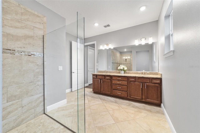 bathroom featuring tiled shower and vanity