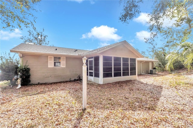 rear view of house with central AC unit, a carport, and a sunroom