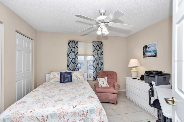 tiled bedroom with a textured ceiling, ceiling fan, and a closet