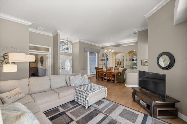 living room with hardwood / wood-style floors, a notable chandelier, and ornamental molding