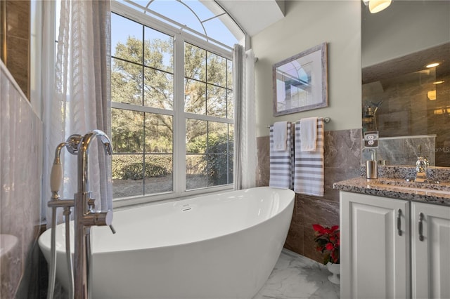 bathroom with a bathing tub, plenty of natural light, tile walls, and vanity