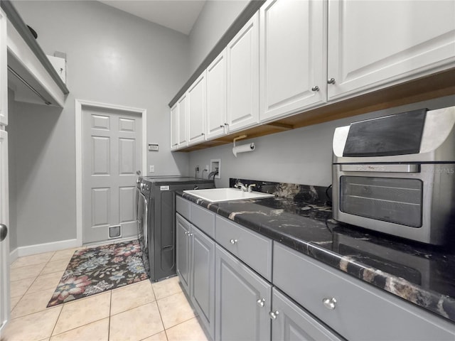 washroom featuring cabinets, light tile patterned floors, washing machine and dryer, and sink