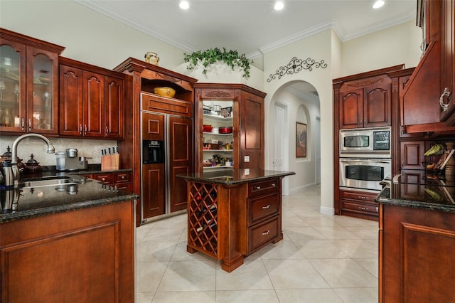 kitchen featuring built in appliances, sink, light tile patterned floors, and dark stone countertops