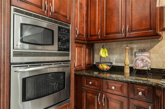 kitchen with backsplash, stainless steel appliances, and dark stone counters