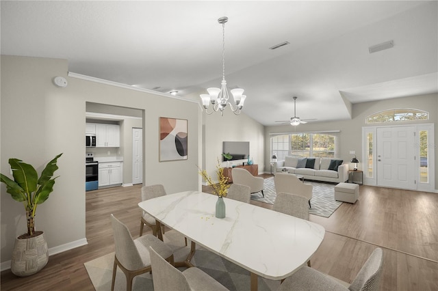 dining space with wood-type flooring, ceiling fan with notable chandelier, and vaulted ceiling