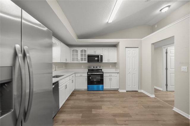 kitchen with appliances with stainless steel finishes, sink, light hardwood / wood-style flooring, white cabinetry, and lofted ceiling