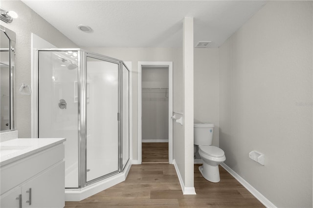 bathroom with a textured ceiling, toilet, a shower with door, vanity, and hardwood / wood-style flooring