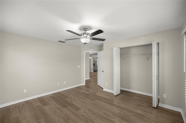 unfurnished bedroom with ceiling fan, a closet, and dark wood-type flooring