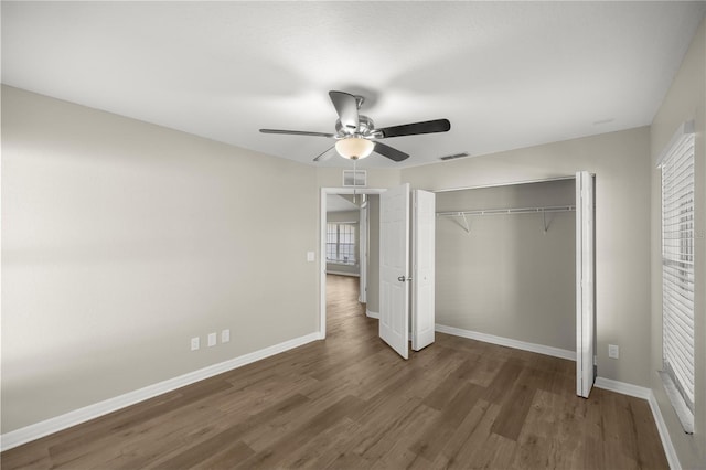 unfurnished bedroom featuring ceiling fan, dark hardwood / wood-style flooring, and a closet