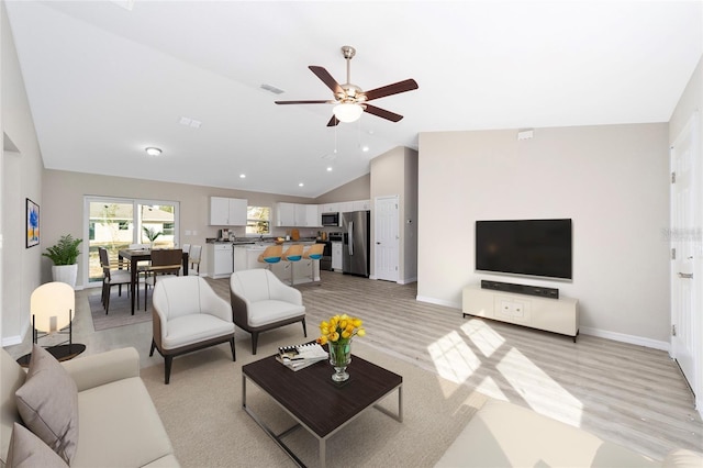 living room with light hardwood / wood-style flooring, vaulted ceiling, and ceiling fan