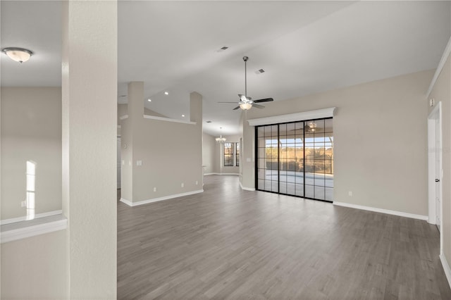 unfurnished living room with lofted ceiling, dark wood-type flooring, and ceiling fan with notable chandelier