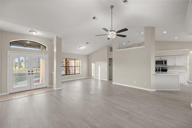 unfurnished living room with french doors, ceiling fan, sink, high vaulted ceiling, and light hardwood / wood-style flooring