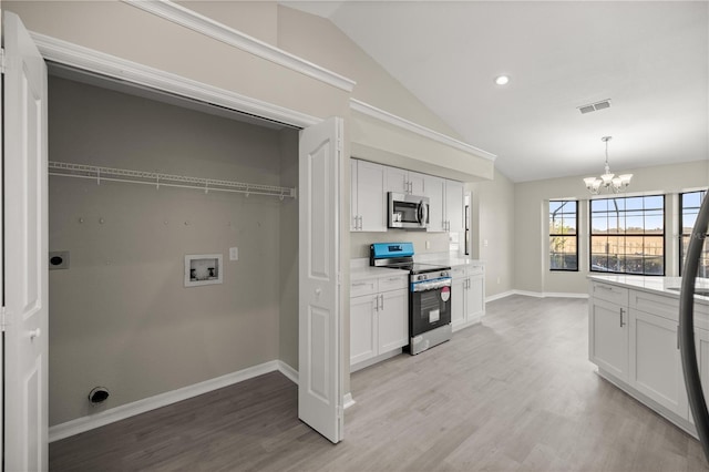 kitchen featuring an inviting chandelier, white cabinets, light hardwood / wood-style flooring, vaulted ceiling, and stainless steel appliances