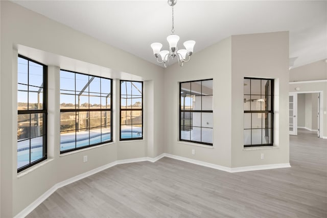 unfurnished dining area featuring a chandelier, vaulted ceiling, and light hardwood / wood-style floors